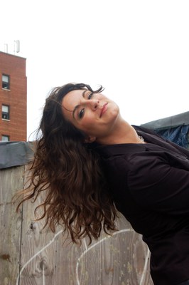 Emily wearing black top with the sky and part wood wall backdrop