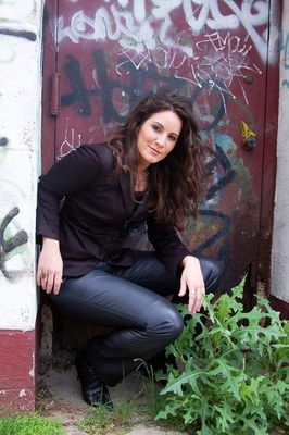 Emily in leather pants infront of metal door